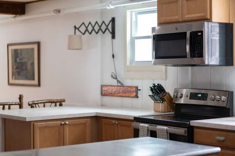 Kitchen counter with an electric range, microwave, knife block, and wall-mounted utensil rack.