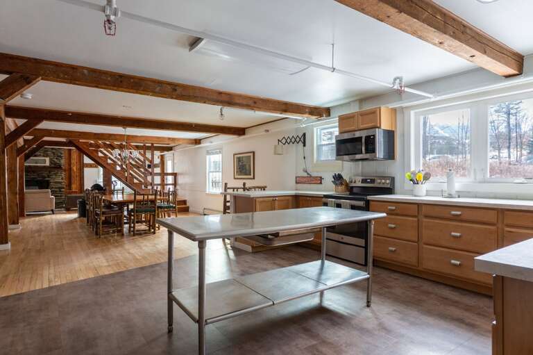 Kitchen view toward the dining area with a prep island, exposed beams, and an open main-level layout.