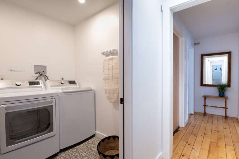 Laundry area with a side-by-side washer and dryer beside the bedroom hallway.