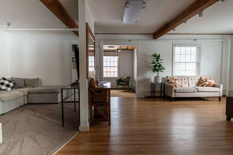 Living room with sectional seating, a windowed sitting area, TV, and open circulation between spaces.