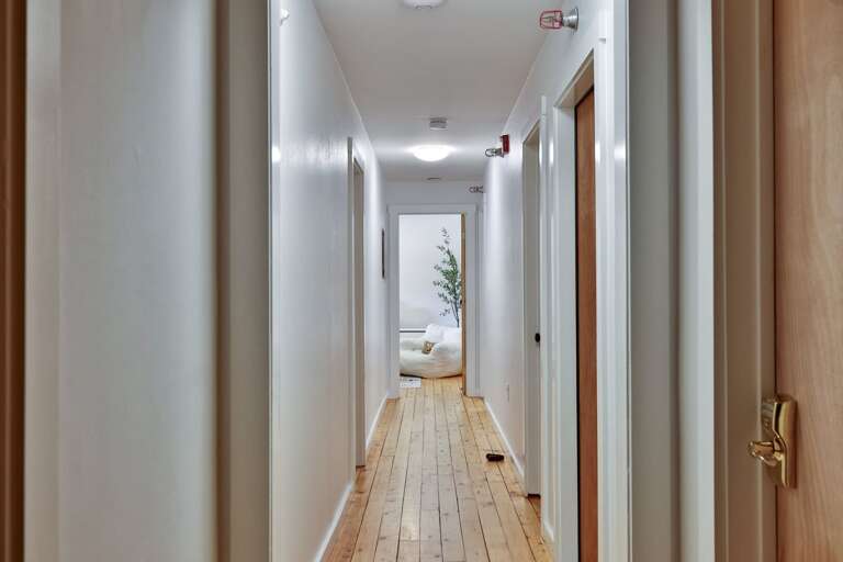 A long upstairs hallway connects all six bedrooms and their bathroom spaces.