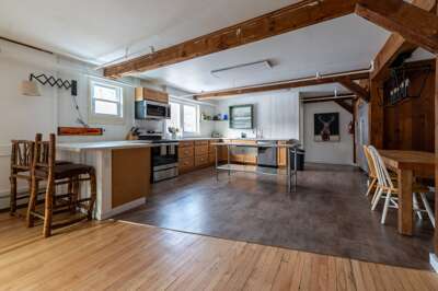 Open kitchen and dining area at The Birch Tree Lodge with exposed timber beams, island seating, and stainless steel appliances.