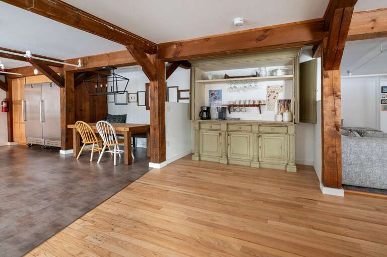 Open kitchen passage with a beverage station, timber posts, and hardwood floors.