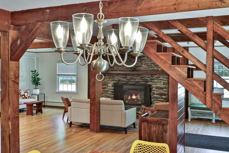 Original timber framing and the stone fireplace give the central gathering area its Vermont lodge character.