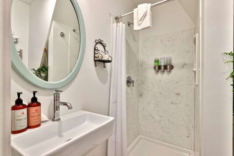 A private full bathroom pairs a compact vanity with a bright walk-in shower.