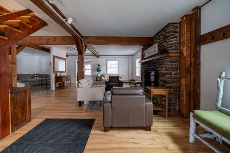 Stone fireplace and living room seating framed by timber columns and hardwood floors.