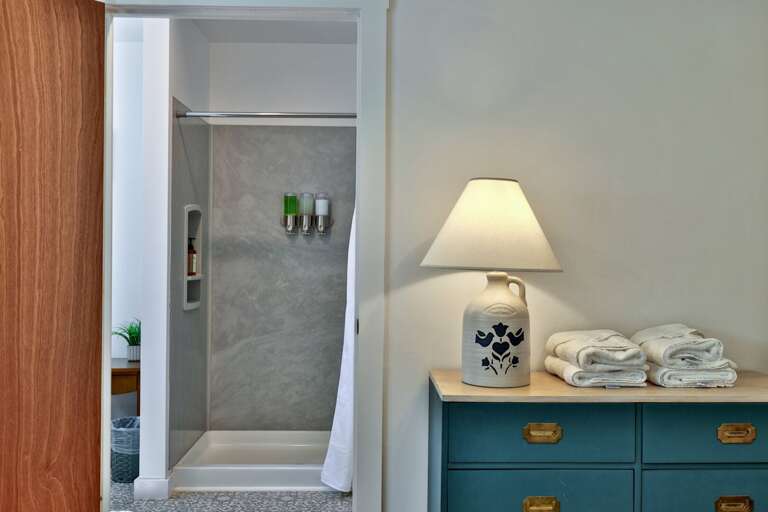 The walk-in shower sits beside a storage cabinet stocked with towels for convenient guest use.