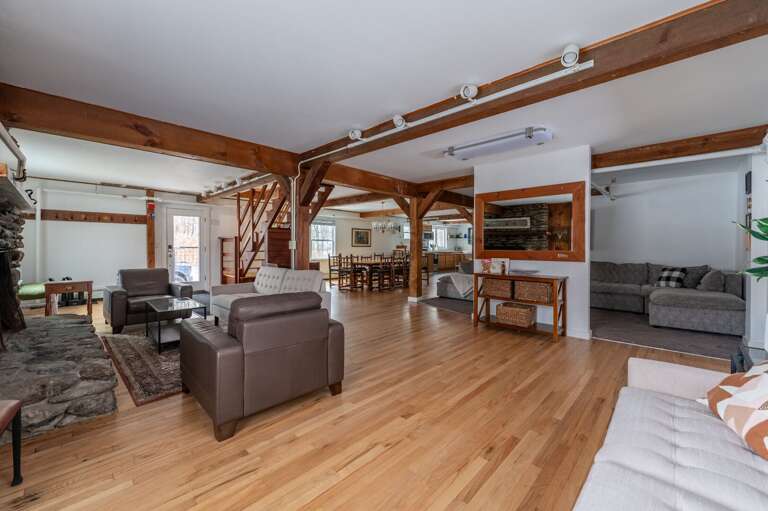 Wide view of the living room, dining area, kitchen, and stone fireplace within the open main level.