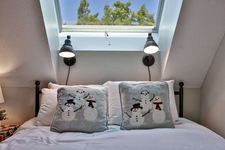 The second bed sits beneath a skylight with its own bedside lamps.