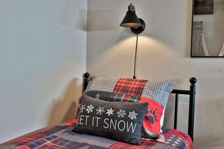 A dedicated wall lamp gives one guest a convenient reading light beside the bed.
