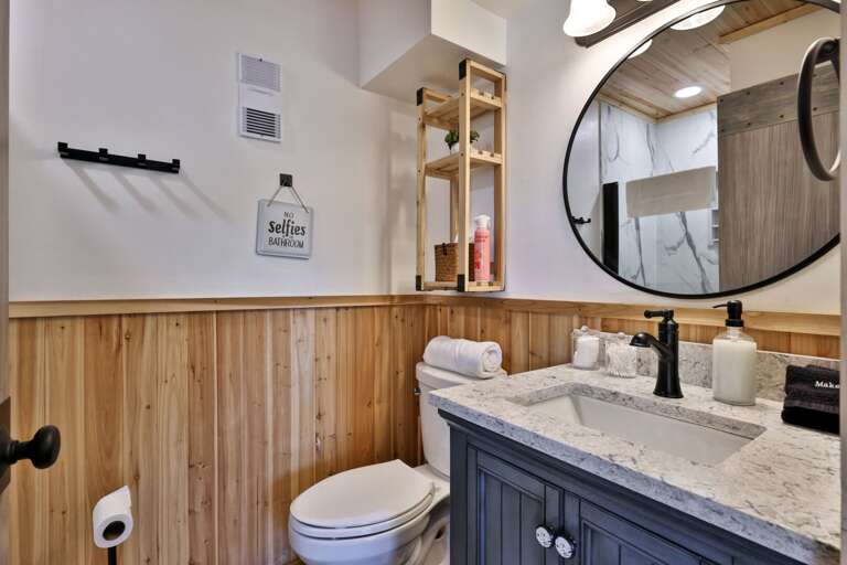 This full bathroom pairs a wide vanity with a walk-in shower and useful open shelving.