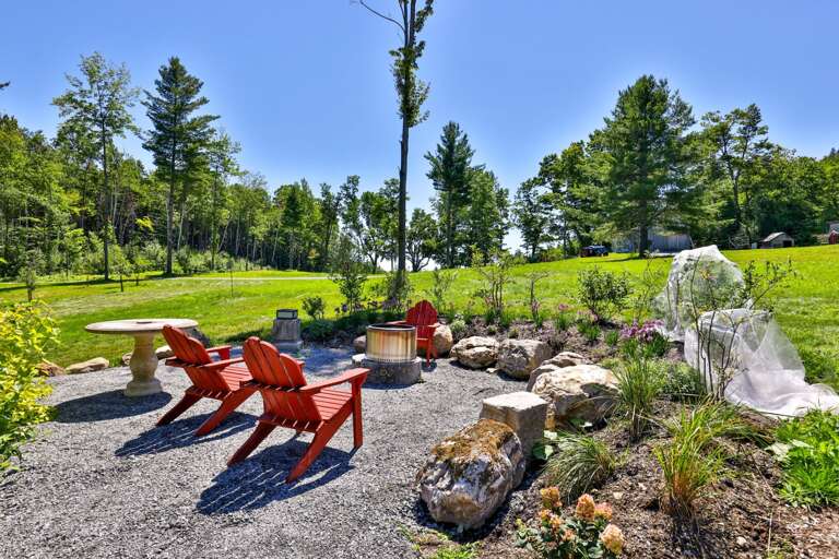 Four Adirondack chairs create an inviting spot for conversation beside the firepit.