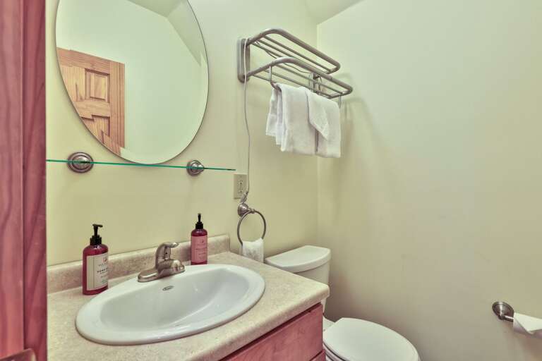 This angle shows the upstairs bathroom's vanity, towel storage, and toilet together.