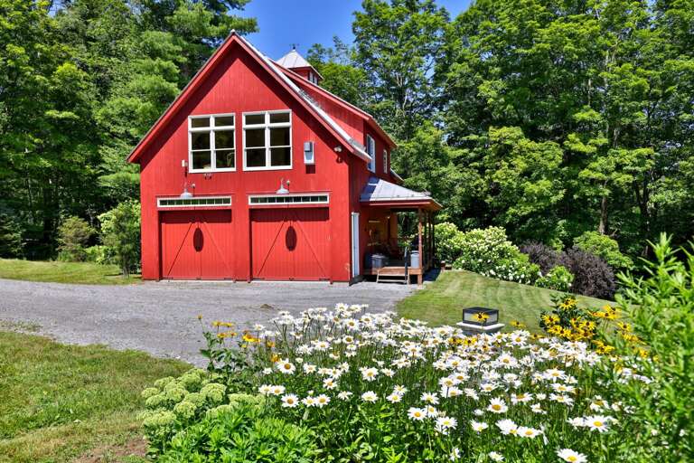 The barn's carriage-style garage doors and upper windows preserve its distinctive rural character.