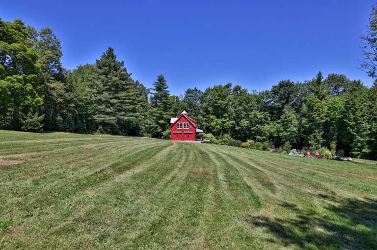 The broad meadow gives the barn a peaceful sense of space beneath a clear Vermont sky.