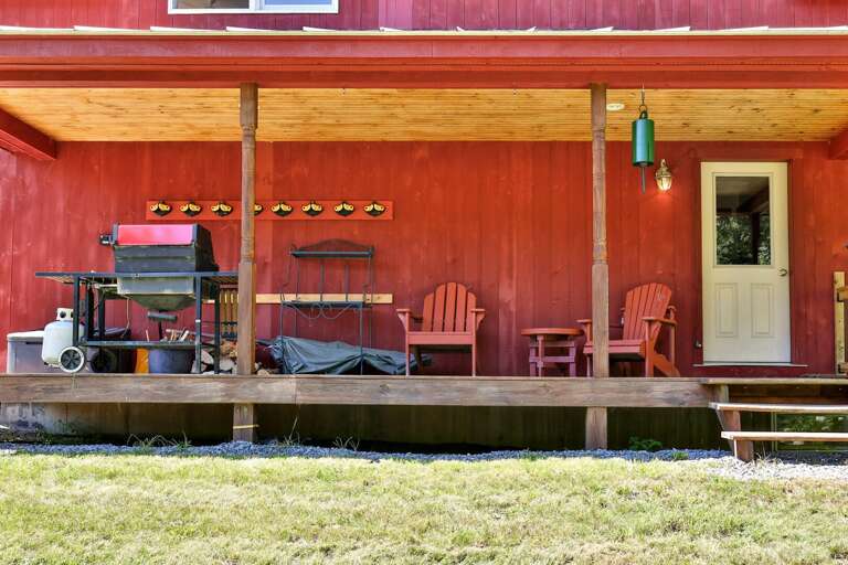A covered porch keeps the grill and outdoor seating sheltered beside the lawn.