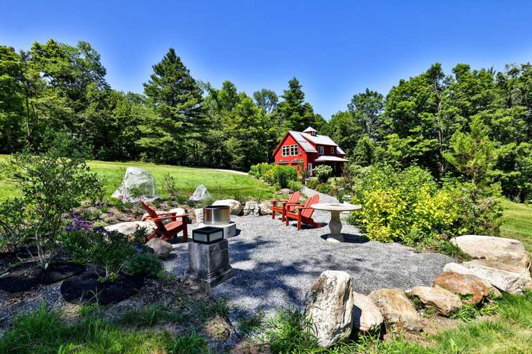 Gather around the landscaped firepit patio while the red barn rises just beyond the stonework.