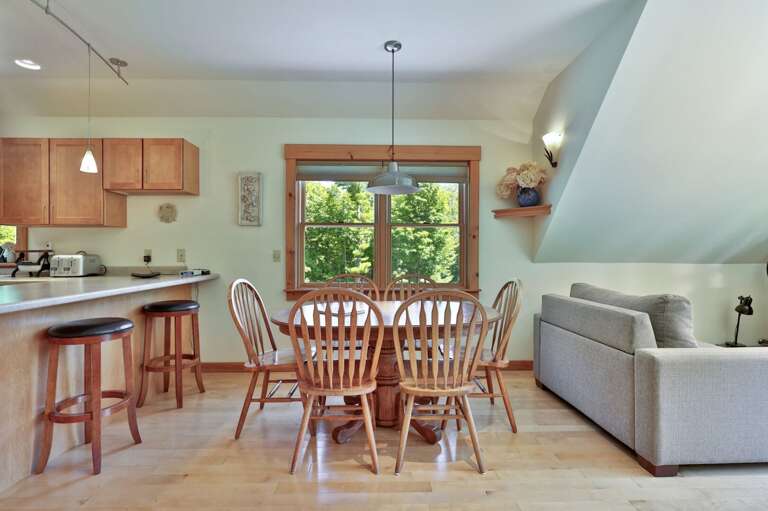 Meals stay connected to the conversation in an open layout joining the dining table, kitchen, and lounge.