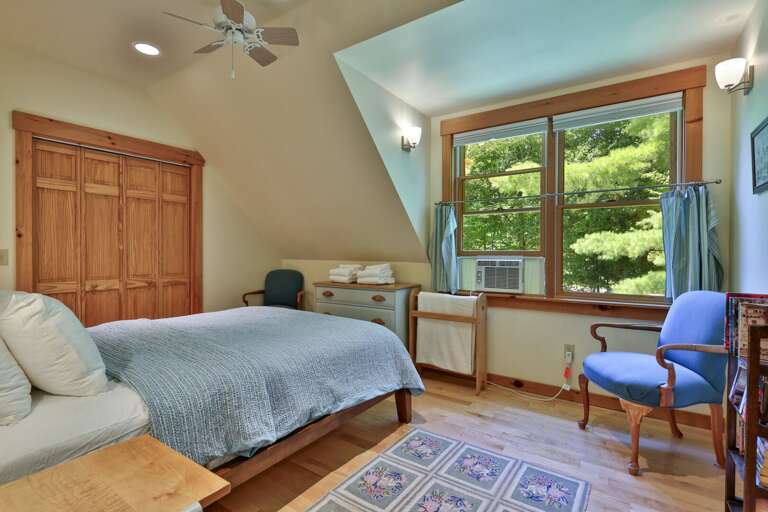 Wake to leafy garden views in a bright upstairs bedroom with warm wood details.