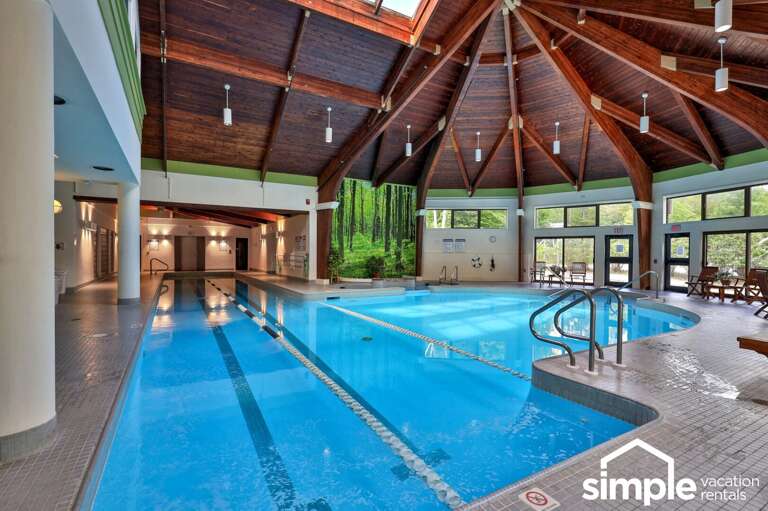 Swim under a vaulted wood ceiling while broad windows look out toward the trees.