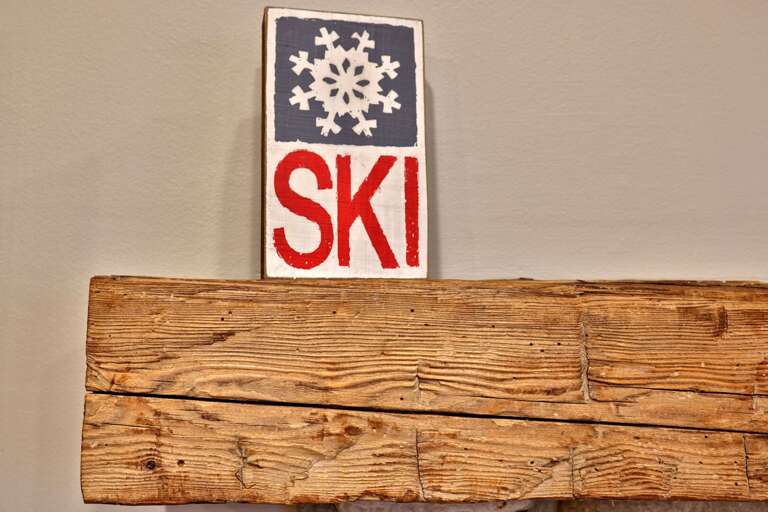 The vintage-style ski sign adds one last wink to the mountain outside.