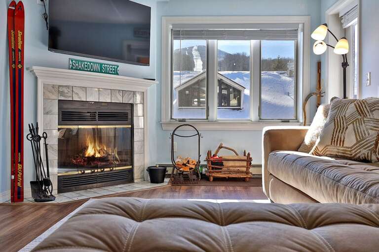 The fireplace sits below the TV, with Pico's snowy trails framed by the nearby windows.