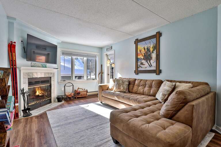 The sectional faces the fireplace and TV, with Pico's slopes visible through the windows.