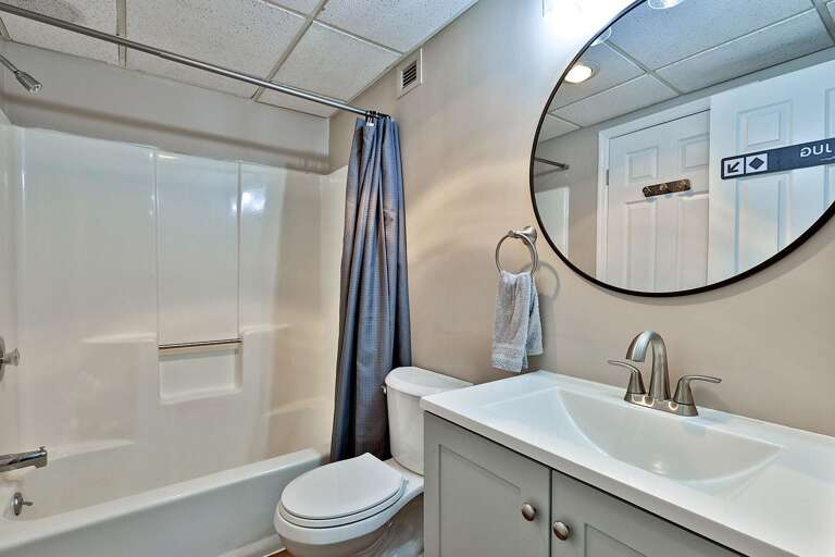 The vanity sits opposite the tub-shower, with the toilet between them.