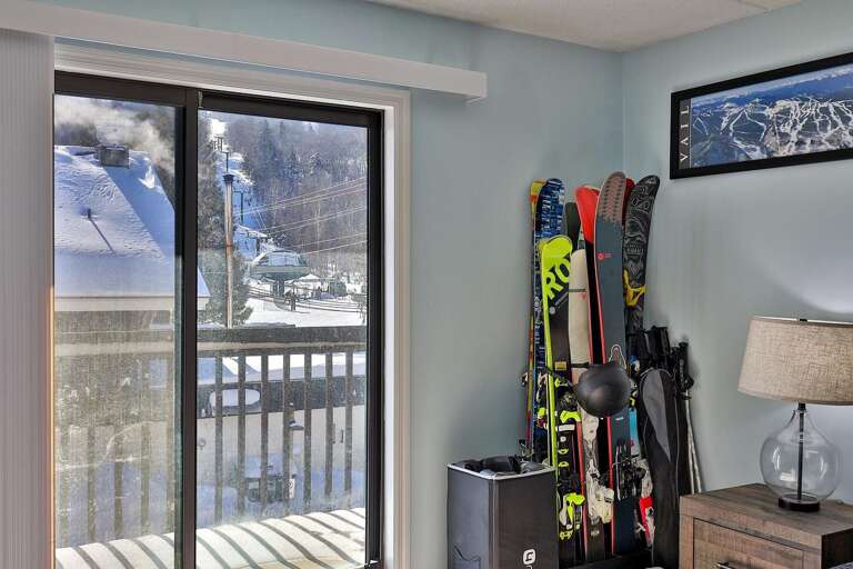 A vertical rack keeps skis beside the sliding doors to the balcony.