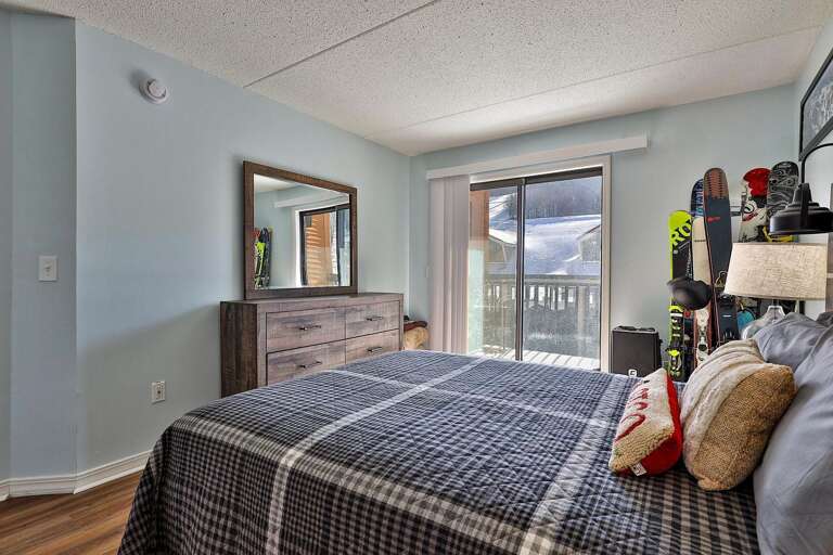 A wide dresser stands opposite the bed, with sliding doors leading to the balcony.