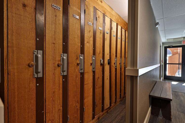 Wood lockers line the corridor opposite a bench near the exterior door.