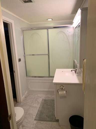 The downstairs bathroom has a shower behind sliding glass doors.