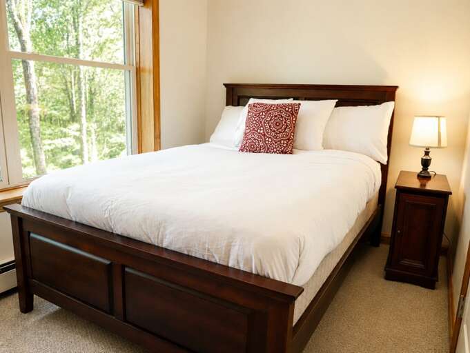 This wider bedroom view shows the window alongside the bed and the nightstand on the other side.