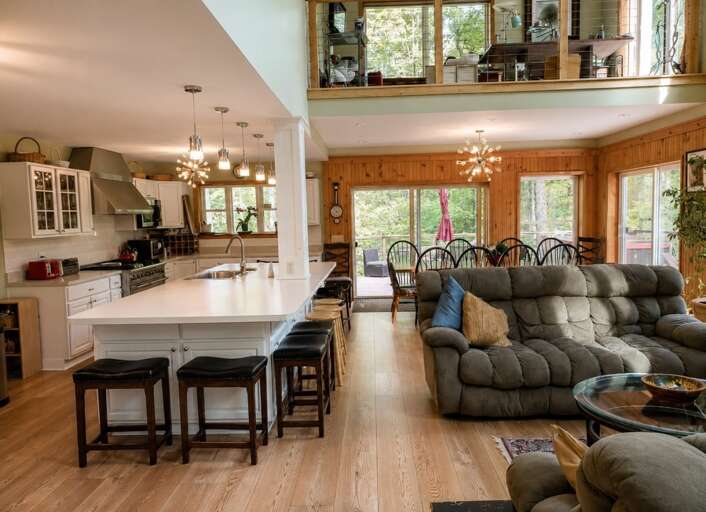 The island stools and living-room sofas are side by side, so the group can gather without all taking the same seat.