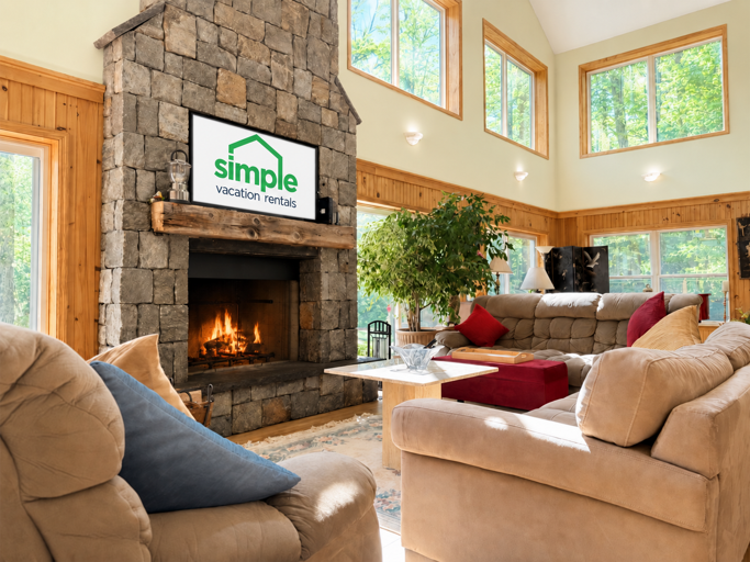 Tall windows surround the fireplace, so an afternoon indoors still comes with a view of the trees.