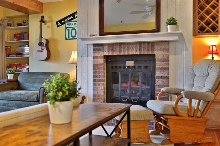 The rocker has a matching footstool beside the brick fireplace.