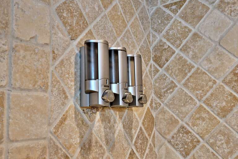 Wall-mounted dispensers keep shower products off the tub edge.