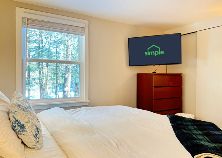Watch TV from the king bed in the primary bedroom, with the trees just outside the window.