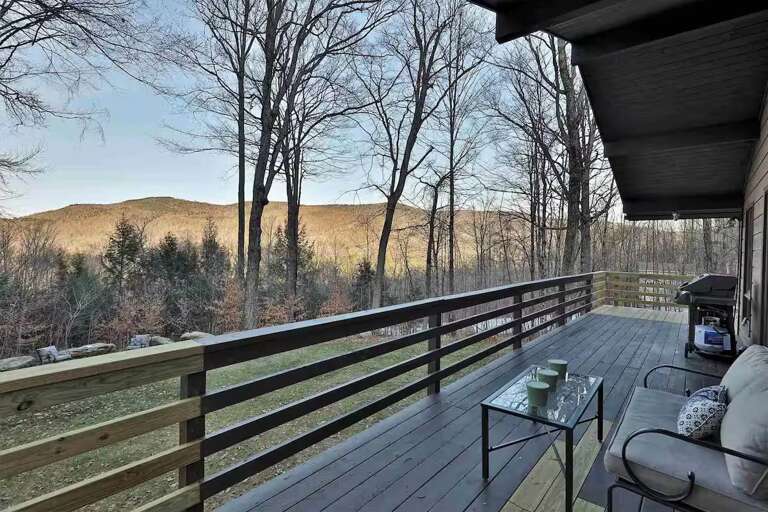 Take a seat on the deck and look out toward the mountains through the trees.