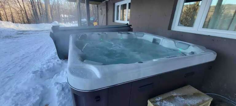 The private hot tub sits beneath the raised deck. Included late December through mid-March; off-season setup is $195. Arrange before arrival.