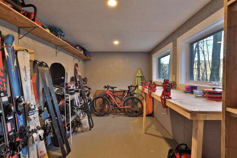 The storage room has wall racks and a workbench. Pictured sports equipment is not advertised as included.