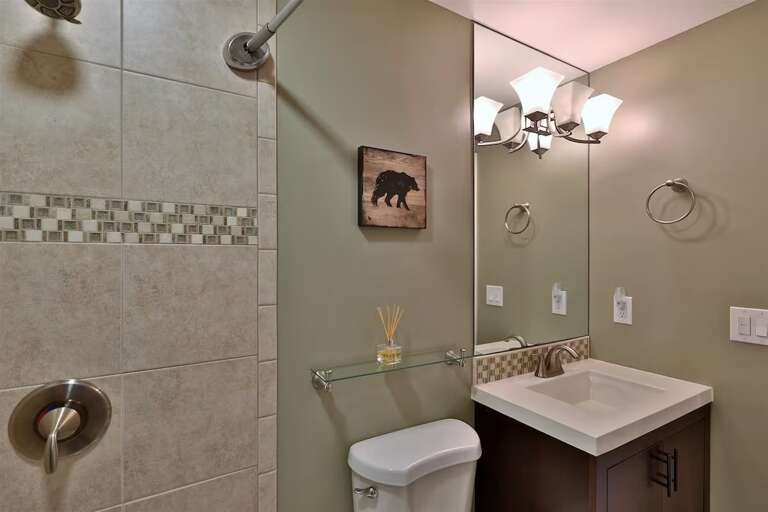 The second bathroom has a broad vanity counter and a large mirror.