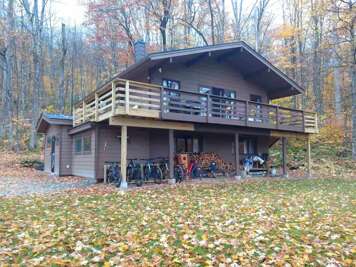 The raised deck wraps around the chalet, with woodland surrounding the yard.