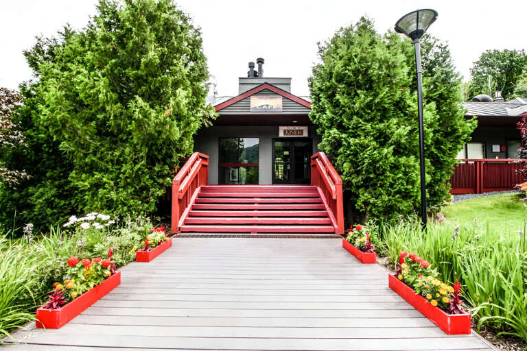 Red steps and a landscaped walkway lead to the entrance marked Sunrise Café. This is a community building, not the Cambridge condo entrance.