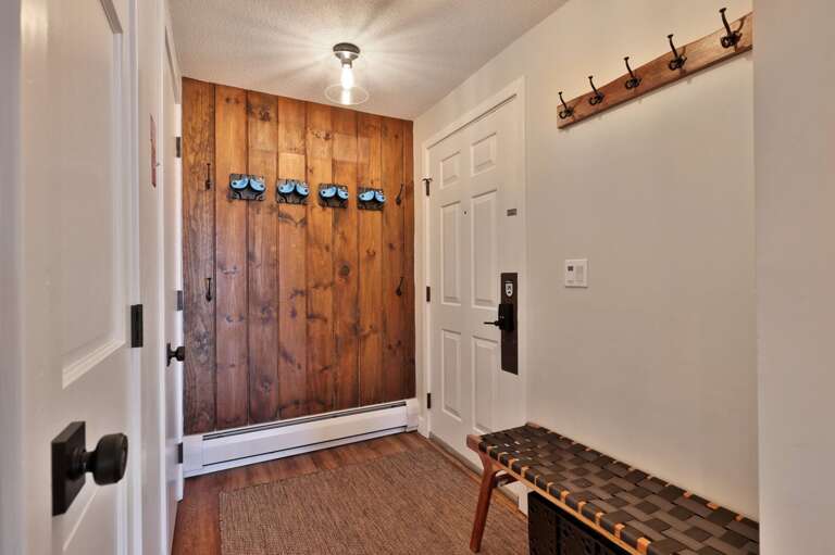The entry has hooks and ski holders, with a bench for taking off shoes before heading inside.
