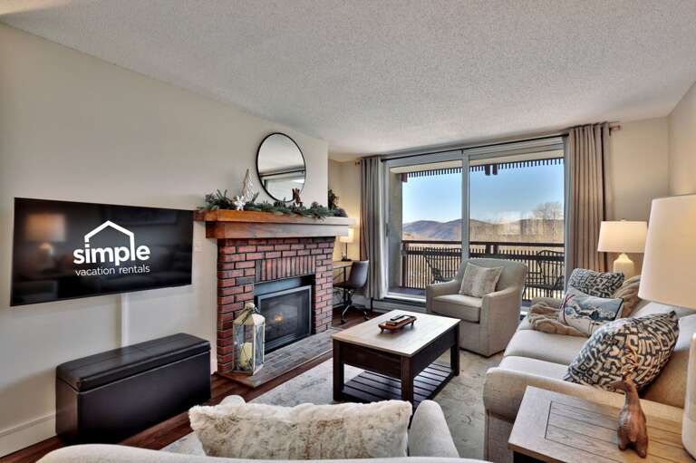 Watch a movie from the living-room seating, with the gas fireplace beside the TV and the balcony beyond.