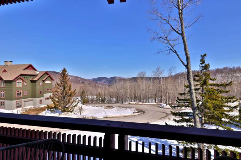 Look over the nearby buildings and snowy grounds toward the wooded ridges beyond.