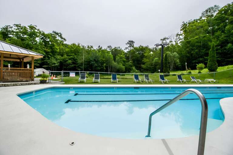 The shared outdoor pool faces trees and a grassy area, with loungers nearby when the facility is open.