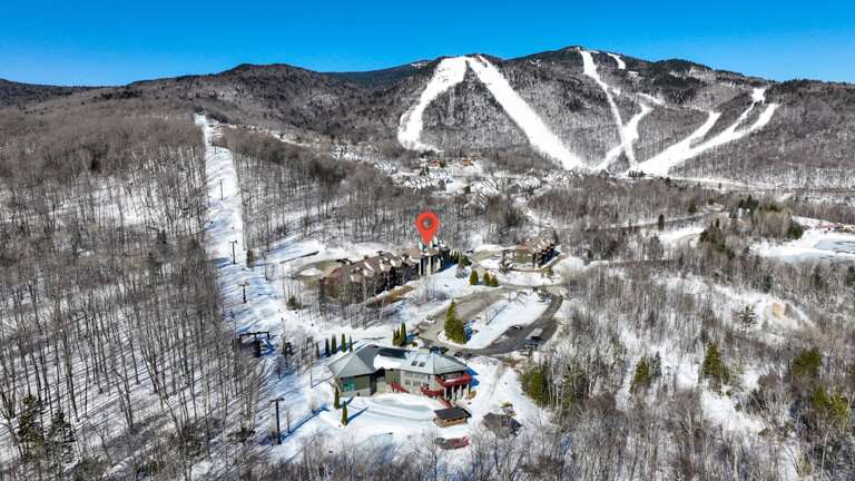 The red marker locates the building group among roads and woods below the ski terrain.