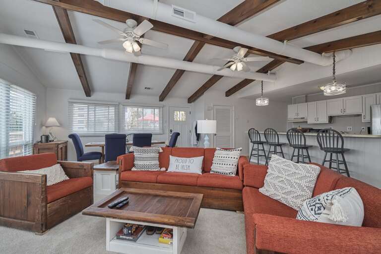 Interior Living Space With Sofas, Ceiling Beams, And Kitchen Counter